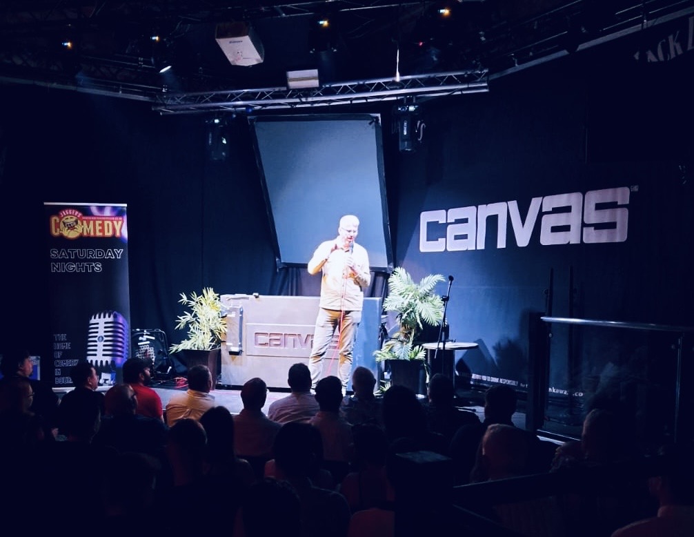 Professional comedy stage setup at Canvas venue with comedian performing to seated audience