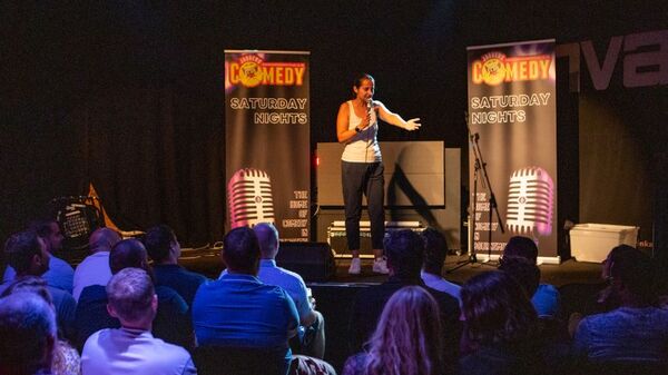 Featured comedian delivering punchlines on stage at Saturday night comedy show
