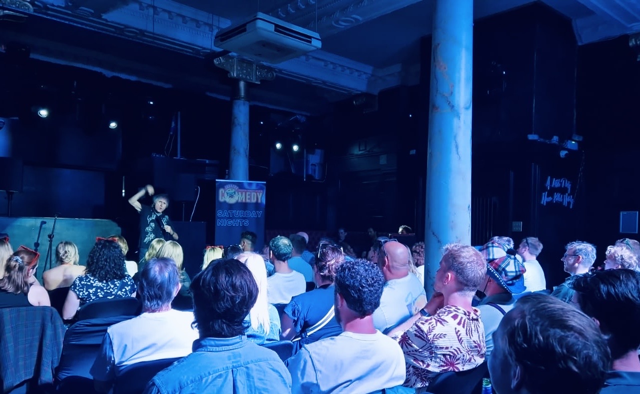 Intimate comedy club atmosphere with blue stage lighting and audience at Canvas Bournemouth